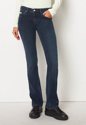 Mørkeblå denim jeans med bred ben-design, fem lommer og en let stræk. Kombineret med sorte snøre-sneakers.