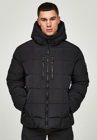 Schwarze Steppjacke mit Kapuze, mit einem quadratischen Steppmuster, zwei vorderen Reißverschlusstaschen und schwarzen Reißverschlüssen. Hergestellt aus glattem, leichtem Material.