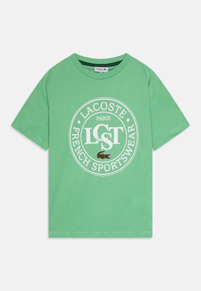T-shirt vert à manches courtes avec col rond, logo blanc circulaire « Lacoste Paris French Sportswear » et petit emblème crocodile vert sur le devant.