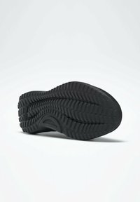 Černá podrážka boty s texturovaným dezénem, vybavená hlubokými drážkami a hladkým okrajem pro lepší přilnavost a odolnost. Materiál působí jako gumový.