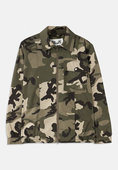 Kurtka w kamuflaż, z zamek błyskawicznym, posiada kołnierz, długie rękawy, elastyczne manszety oraz kieszeń na piersi. Kolory to zieleń, beż i czerń.