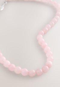 Rose quartz bead necklace featuring smooth, round beads in soft pink, showcasing a uniform shape and consistent, translucent texture.