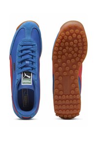 Baskets Puma bleu et rouge avec un dessus en daim et en maille, semelle en caoutchouc rond avec un motif en pointillés et fermeture à lacets.