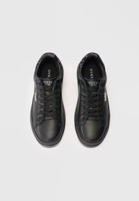 Ein Paar schwarze Guess Schnürsneaker mit Logo auf der Zunge und an der Seite sowie Paillettenverzierungen auf der Ferse, von oben auf einem weißen Hintergrund gezeigt.