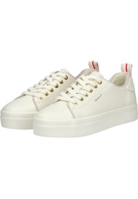 Sneaker in pelle bianca con finitura liscia, punta arrotondata, occhielli dorati e un accento rosa sulla linguetta del tallone; presenta una suola in gomma testurizzata.
