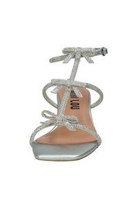 Sandal con stiletto argento con cinturini decorati, dettagli a fiocco e punta metallica lucida. La soletta è di colore nude con un marchio elegante.