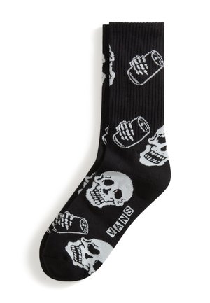 Sorte Vans-strømper med hvide mønstre af kranie og sodavandsdåse, ribbet tekstur og Vans-logo nær tåområdet.