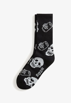 Sorte Vans-strømper med hvide mønstre af kranie og sodavandsdåse, ribbet tekstur og Vans-logo nær tåområdet.