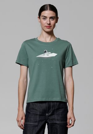 T-shirt en coton vert avec un col rond, des manches courtes et un graphisme blanc représentant un astronaute sur un avion en papier.