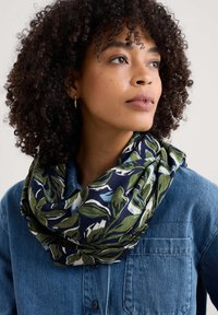 Sciarpa a fantasia floreale in blu navy, con foglie verdi e blu, realizzata in un morbido tessuto, avvolta liberamente attorno al collo.