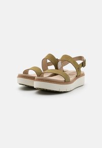 Olive green suede sandals with cross straps, adjustable buckle, and a white platform sole featuring textured accents.