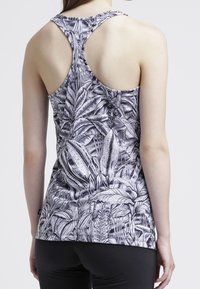 Sleeveless tank top in black and white with a botanical leaf pattern. Features a racerback design and a fitted silhouette. Soft fabric texture.
