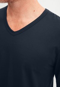Navyblaues V-Ausschnitt-T-Shirt aus leichtem, weichem Stoff mit glatter Textur und minimalen Nähten, das eine taillierte Passform um den Hals bietet.