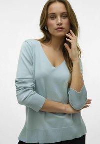 Maglione azzurro chiaro con scollo a V e maniche lunghe, polsini a costine e orlo leggermente svasato. Tessuto morbido e liscio con una vestibilità comoda.
