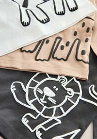 Trzy bawełniane koszulki ułożone jedna na drugiej: biała z czarnym wzorem zwierzęcym, beżowa z abstrakcyjnymi kształtami oraz ciemnoszara z białą ilustracją lwa.