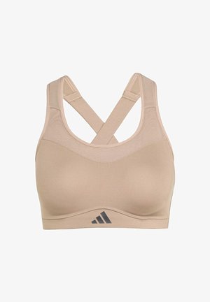 Sujetador deportivo beige con una textura suave, tirantes cruzados en la espalda y un logotipo sutil en la banda inferior. Tejido suave para comodidad y soporte.