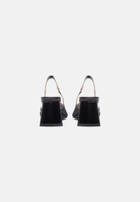 Crne slingback sandale od lakirane kože s kvadratnom petom, glatkom teksturom i minimalnim detaljima.