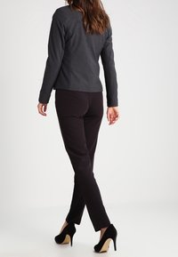 Ciemnoszary żakiet dopasowany, zestawiony z czarnymi spodniami slim fit i szpilkami. Gładki materiał, bez widocznych wzorów.