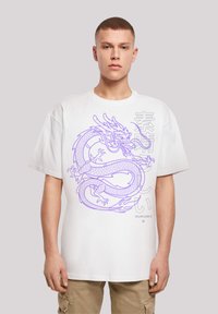 White oversized t-shirt featuring a purple dragon graphic and Asian text. The fabric appears soft, with a relaxed fit and short sleeves.