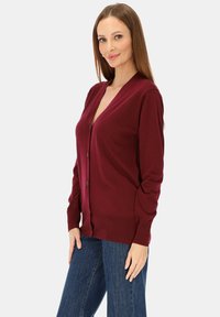 Bordowy sweter na guziki wykonany z miękkiej dzianiny, z głębokim dekoltem w kształcie litery V, długimi rękawami i prążkowanym dołem.