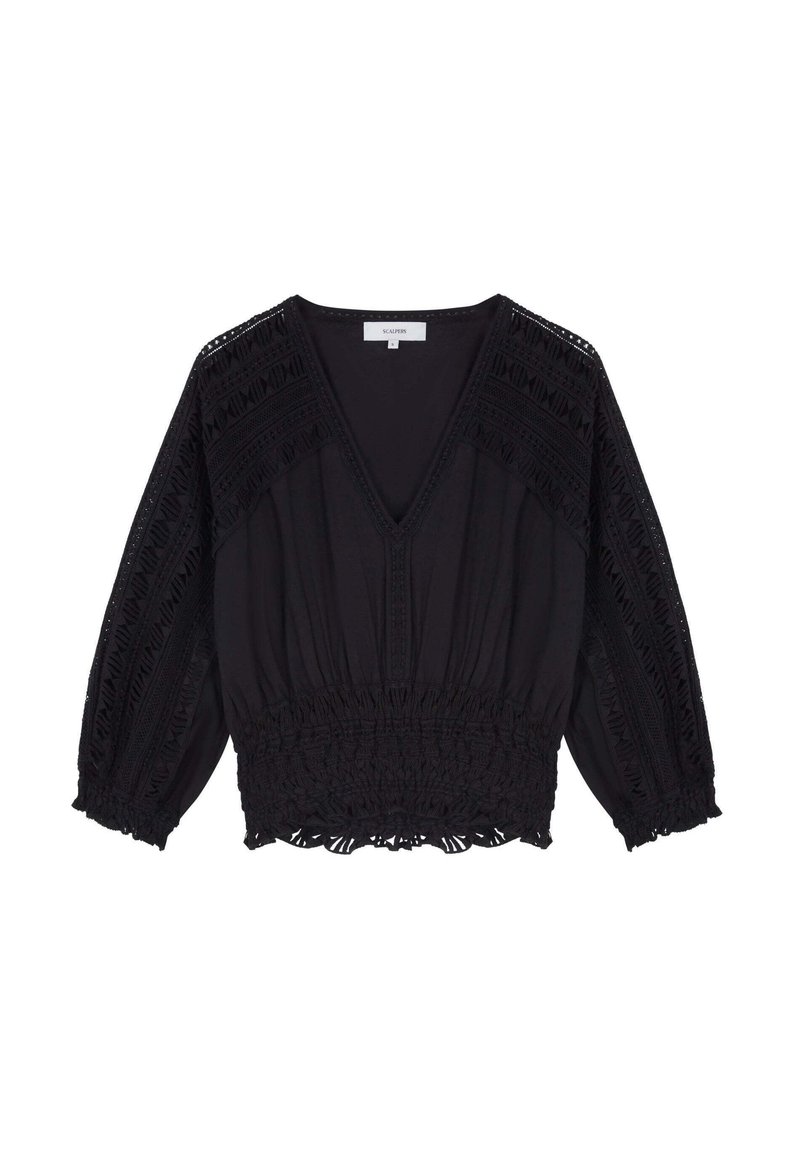 Blouse noire avec un col en V, en tissu texturé, taille élastique et des détails en dentelle décoratifs sur les manches et les épaules.