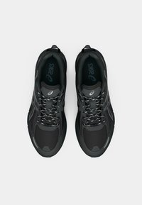 Black athletic shoes with mesh and synthetic overlays, featuring a textured sole, reflective accents, and contrasting grey laces.