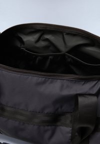 Black messenger bag with a zippered opening, featuring a smooth exterior, fabric straps, and a mesh pocket inside.