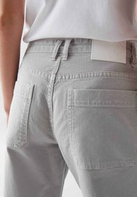 Jeans in denim grigio con vita alta, dotati di due tasche posteriori e di un'etichetta in pelle rettangolare in vita. Tessuto texture.