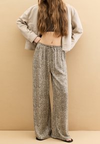 Pantalon long à jambes larges avec imprimé léopard, confectionné en tissu léger. Il possède une taille élastique et une coupe ample.