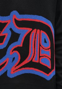 Maglione nero con grafiche audaci e colorate in rosso e blu. Il design presenta forme intricate con contorni definiti e texture.