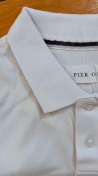 Weißes Poloshirt aus strukturiertem Stoff, mit einem Kragen und drei Knöpfen. Ein dunkler Streifen akzentuiert den Kragen, mit einem Etikett, auf dem "PIER" steht.