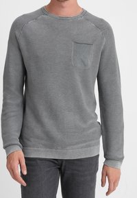 Grauer Rundhals-Pullover aus strukturiertem Stoff, mit geripptem Kragen und Bündchen sowie einer Brusttasche. Figurbetontes Design, nahtlose Schultern, weicher Griff.