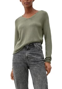 Pull tricoté vert olive à col en V, avec une texture en côtes et des manches longues, accompagné d'un jean en denim noir taille haute.
