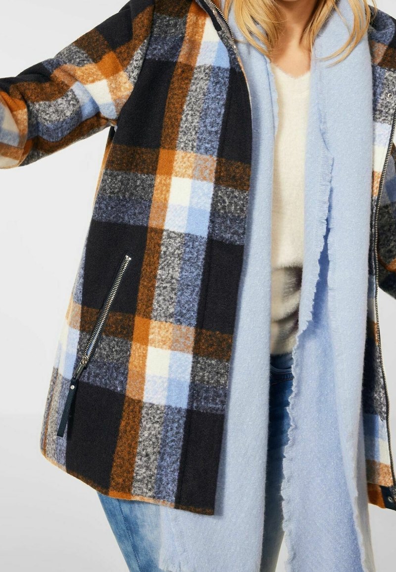 Rutigt ullrock med nyanser av marinblått, orange och blått, med en dragkedjeficka och en mjuk, kontrasterande ljusblå scarf.