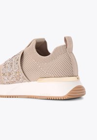 Sneaker lavorato a maglia beige con superficie testurizzata, arricchito da dettagli in oro e cristallo; presenta una suola bianca e dettagli dorati sul tallone.