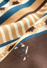 Tissu à motifs présentant des rayures bleues, brunes et beiges avec des motifs floraux. Des textures variées créent une apparence visuellement dynamique.