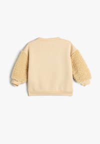 Jasnobeżowy sweter z teksturowanymi, puszystymi beżowymi rękawami. Ściągacz przy dekolcie i mankietach. Gładki materiał korpusu, casualowy design odpowiedni do noszenia na warstwy.