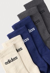 Σετ με τέσσερα ζευγάρια κάλτσες crew σε κρεμ, σκούρο μπλε, σκούρο γκρι και ανοιχτό γκρι, με ριμπ υφή και το λογότυπο "adidas" σε μαύρο.