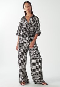 Black and white checkered patterned oversized shirt and wide-leg pants set, featuring a collar and relaxed fit with soft fabric texture.