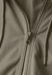 Olivově zelená bunda na zip s lesklým stříbrným zipem, jemnou texturou látky a kontrastním šitím podél okrajů švů.