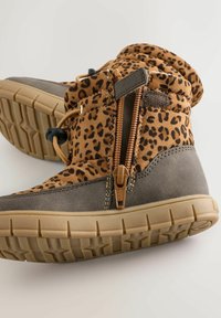 Cizme până la gleznă cu imprimeu de leopard maro, cu un inferior din piele gri, având un fermoar lateral, cordon elastic și talpă din cauciuc texturat.