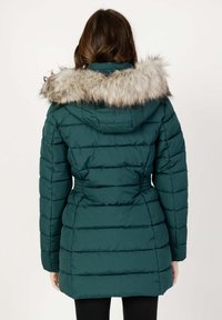 Giacca imbottita teal con cappuccio in pelliccia sintetica, design trapuntato, vita elasticizzata e maniche lunghe. Texture liscia con un aspetto caldo e isolato.