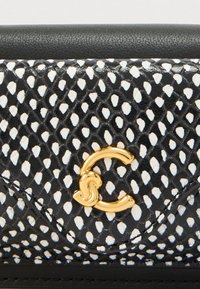 Μονόχρωμη ασπρόμαυρη τσάντα με υφή δέρματος φιδιού, που διαθέτει έναν χρυσό κυκλικό κούμπωμα και μαύρες δερμάτινες λεπτομέρειες.