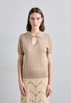 Top tricotat bej cu mâneci puff scurte, guler ascuțit și o decupare în formă de cheiță. Textură netedă, croi ajustat. Asortat cu o fustă din dantelă.