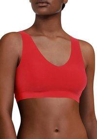 Roter Sport-BH mit V-Ausschnitt, breiten Trägern und nahtlosem Design. Hergestellt aus dehnbarem Stoff, bietet er eine glatte Textur und eine figurschmeichelnde Form.