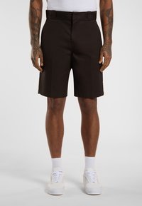 Brown shorts with a tailored design, made of woven fabric, featuring a flat front, belt loops, and side pockets. Paired with white sneakers.