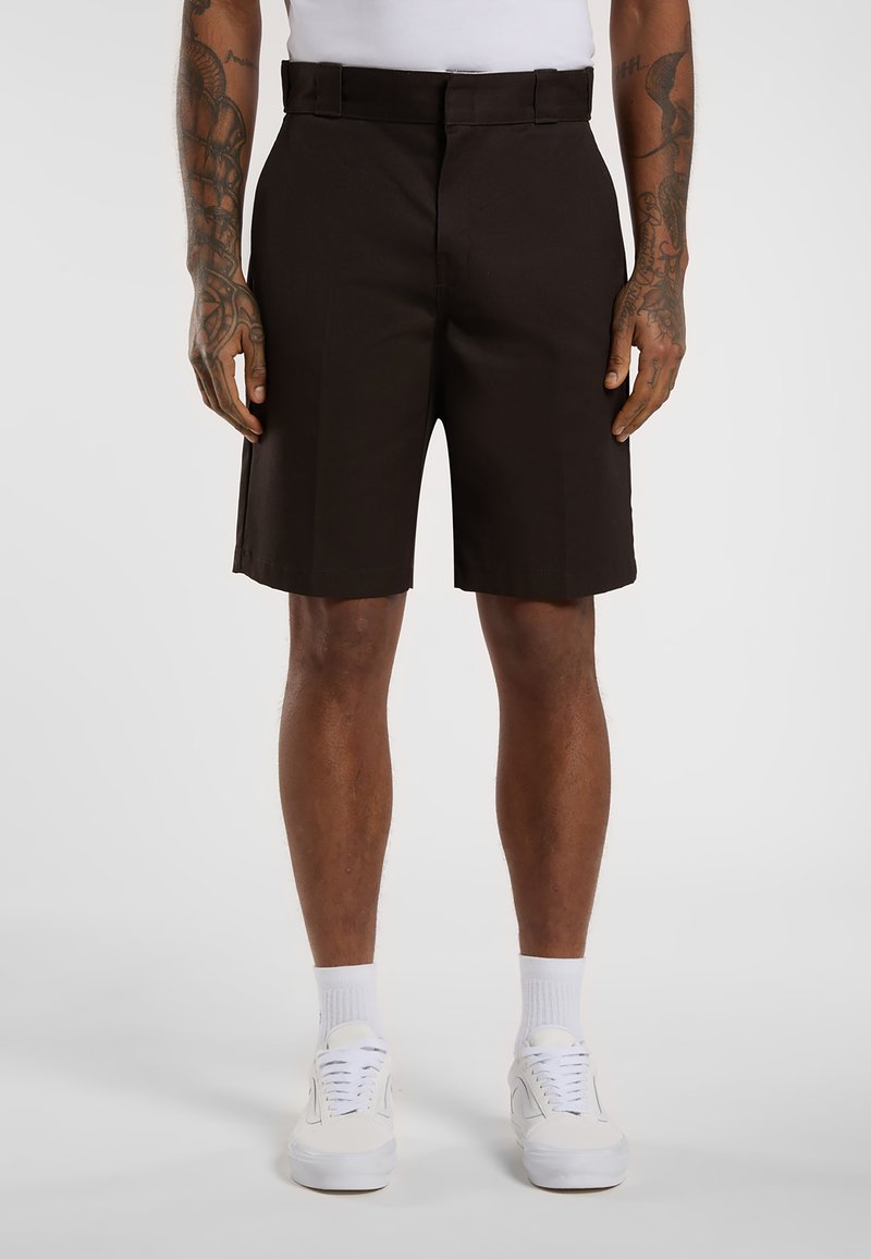 Brown shorts with a tailored design, made of woven fabric, featuring a flat front, belt loops, and side pockets. Paired with white sneakers.