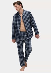 Conjunto de pijama a rayas en azul marino y blanco que incluye una camisa de botones y pantalones a juego. La tela es suave, ligera y transpirable.