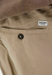Béžice od teksturiranog materijala sa stražnjim džepom s crnim dugmetom i etiketom s natpisom "JACK & JONES EST. 1990."