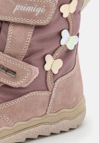 Stivale in suede e tessuto rosa con chiusura a strappo e applicazioni decorative a farfalla. Suola testurizzata con un motivo ondulato.